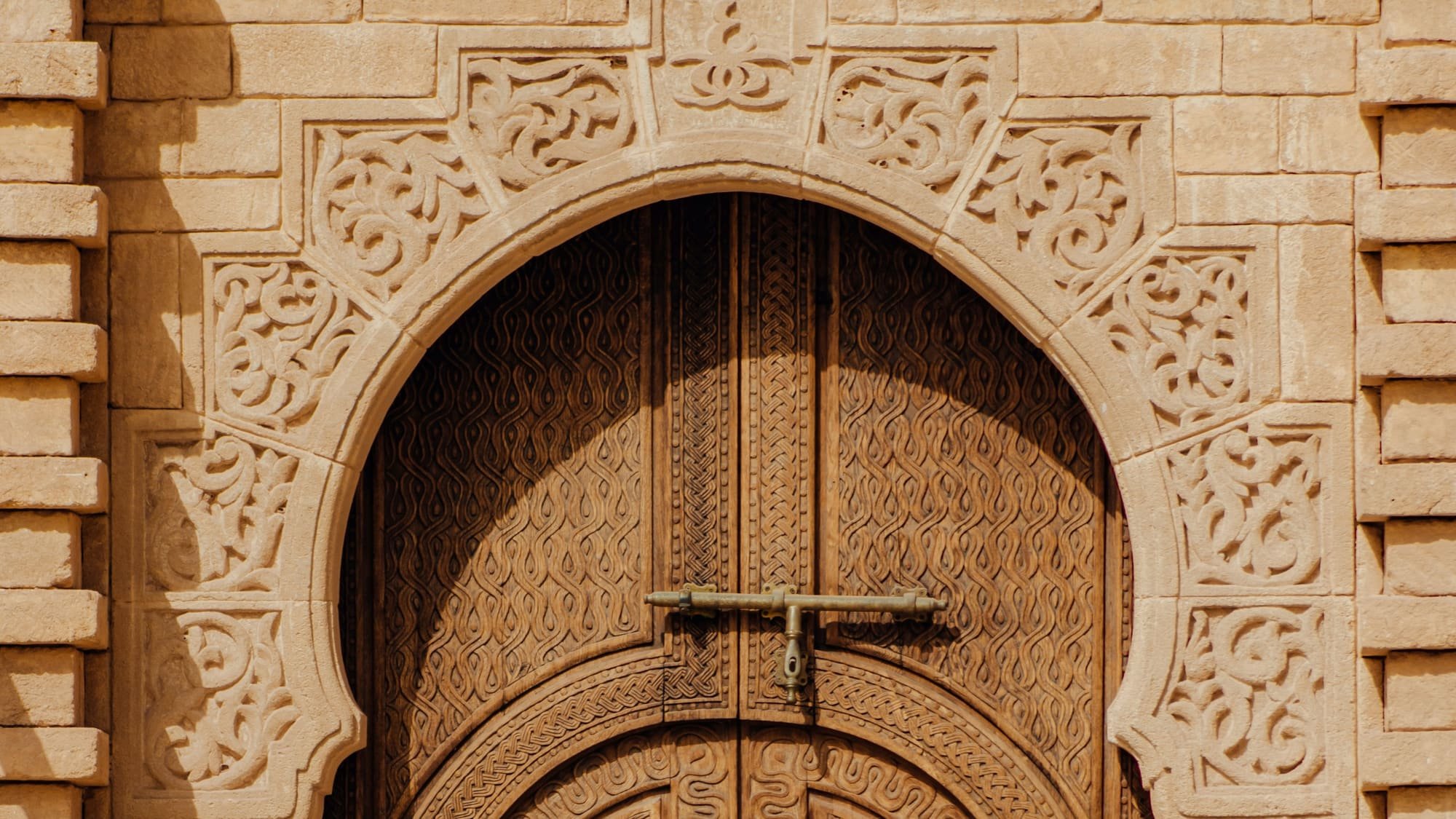 Porte en bois sculpté sous un arc outrepassé encadré de stuc ciselé
