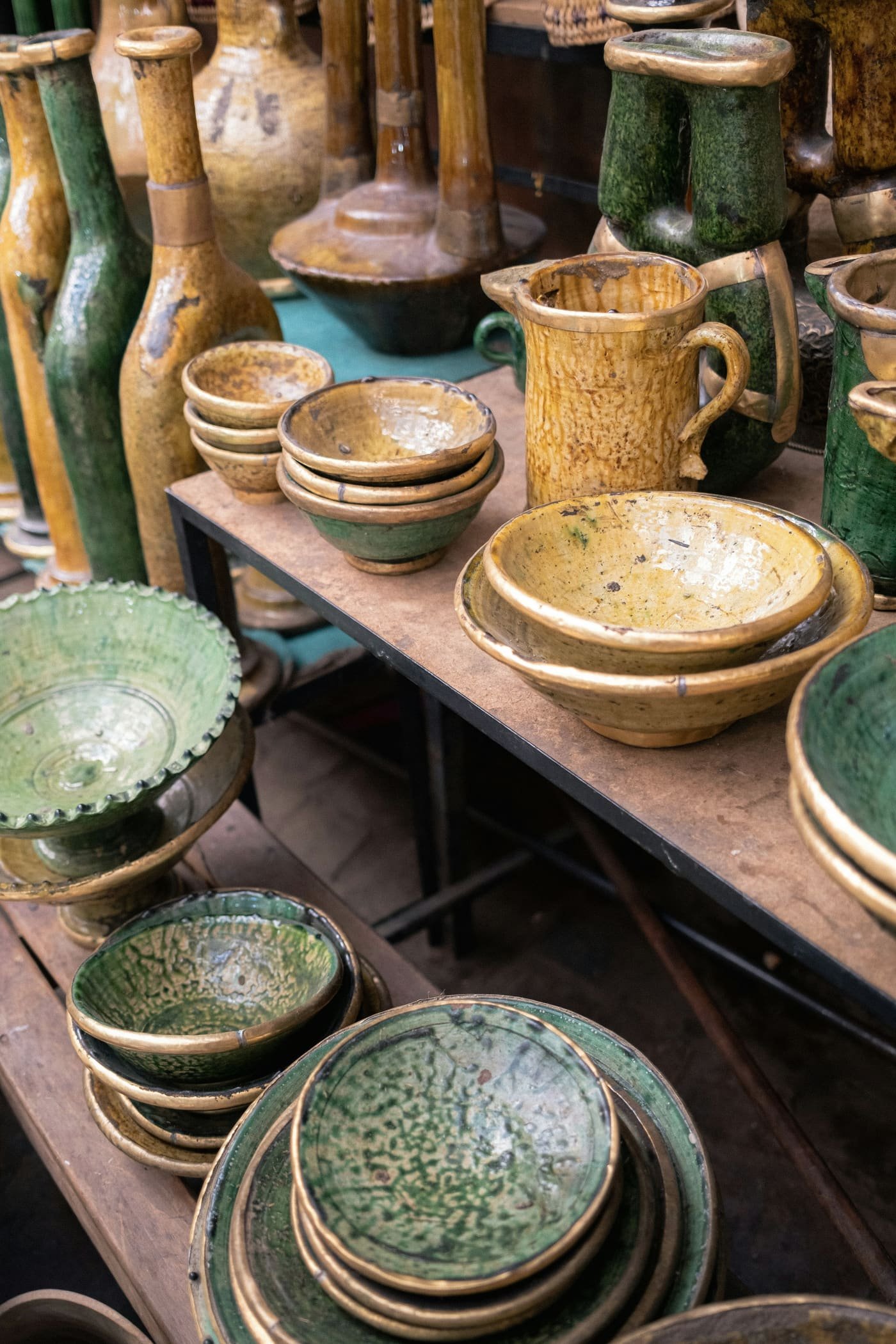 Bols et jarres en céramique émaillée verte et ocre sur une table en bois