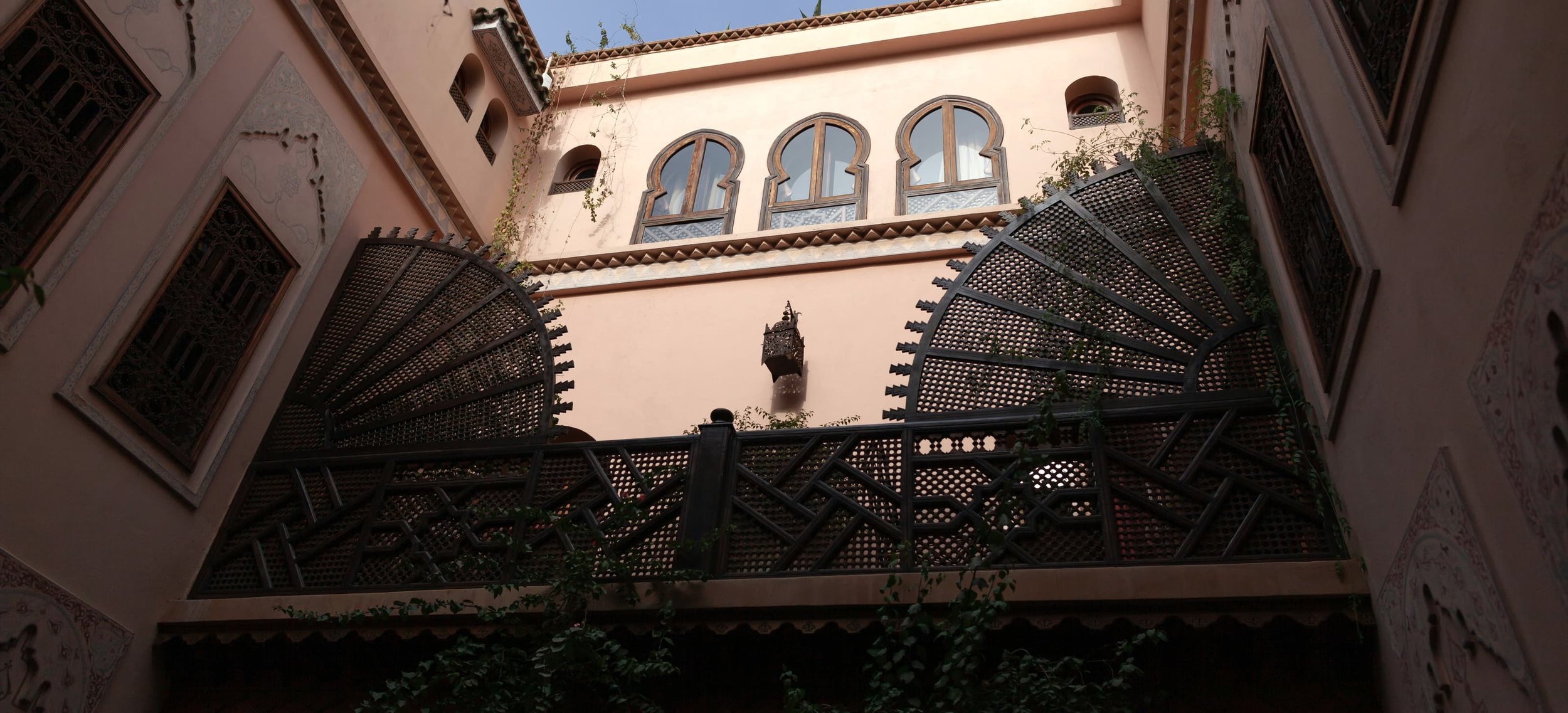 Riad courtyard with wooden mashrabiya screens and pink tadelakt walls
