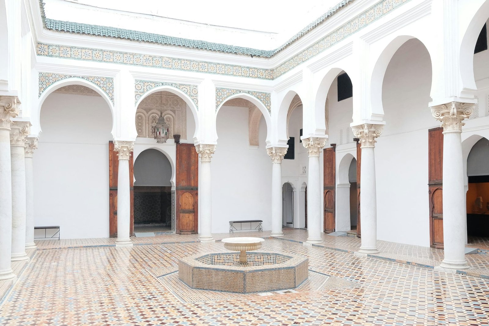 Cour intérieure d’un riad marocain bordée d’arcades blanches et d’une fontaine