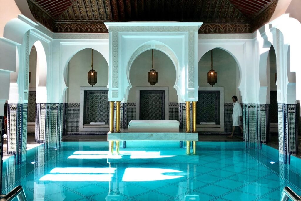 Indoor pool of a hotel in Marrakech, with white arcades, zellige and lanterns