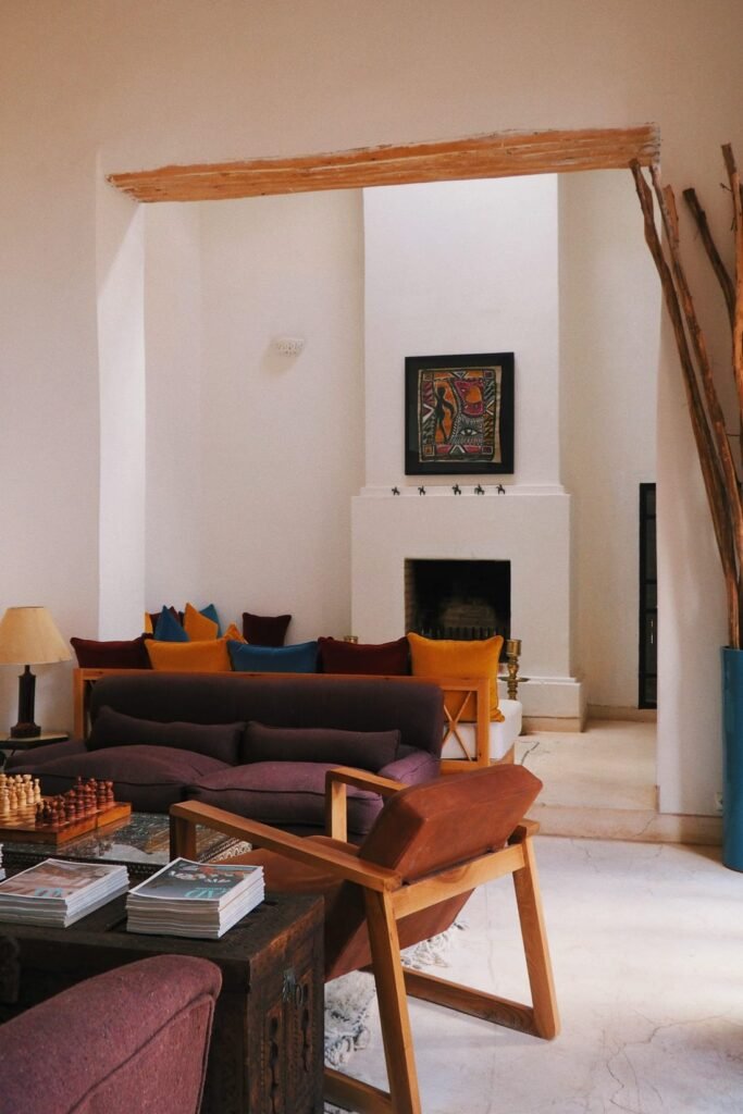 White-walled living room with a fireplace, earth-toned sofas and a wooden armchair, near Marrakech