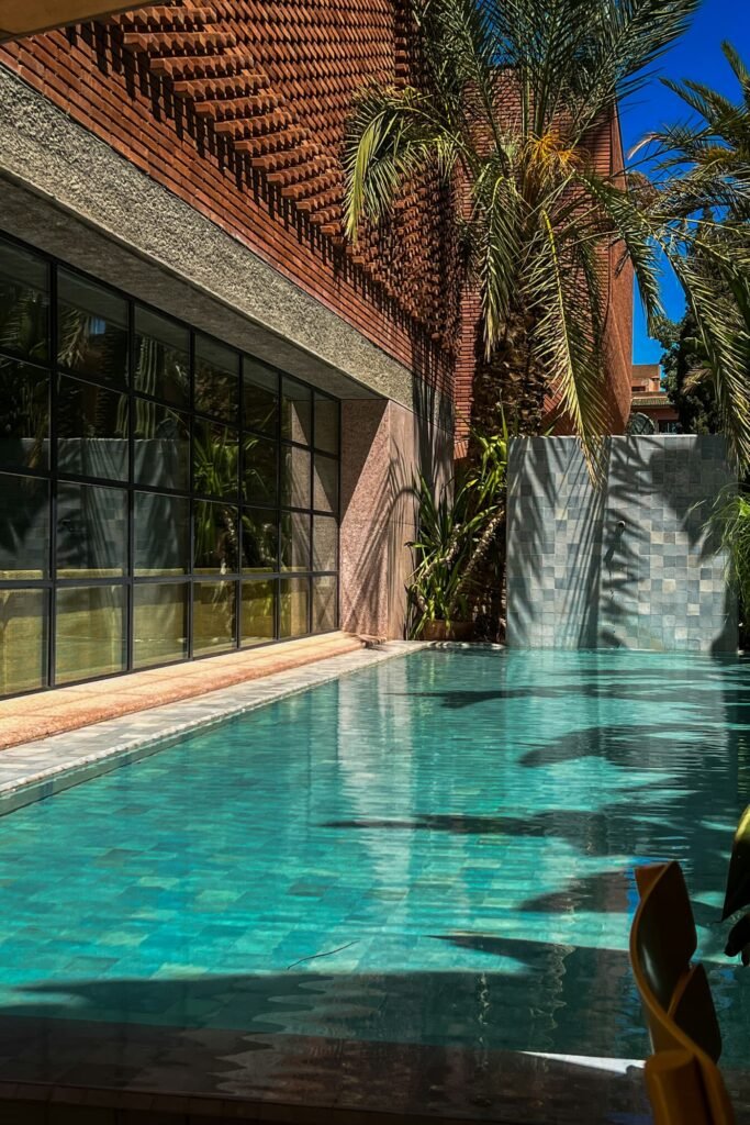 Emerald pool of a contemporary residence in Marrakech, with picture windows and palm trees